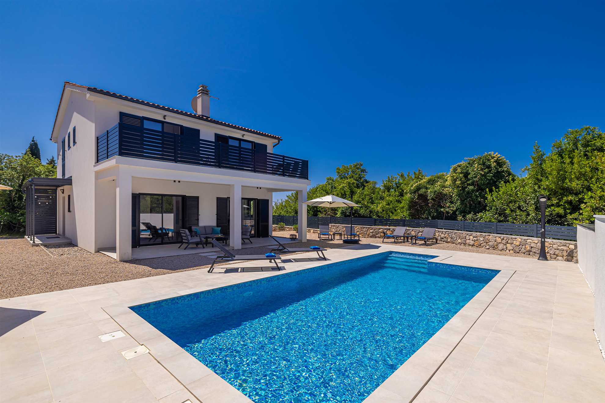 Ferienhaus SARA in Kras mit Außenpool, Sonnenliegen und Sonnenschirm.