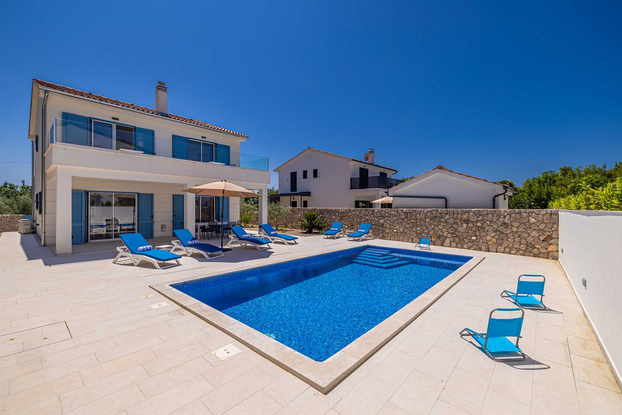 Ferienhaus DAN in Kras mit Pool, Sonnenliegen und Sonnenschirm.