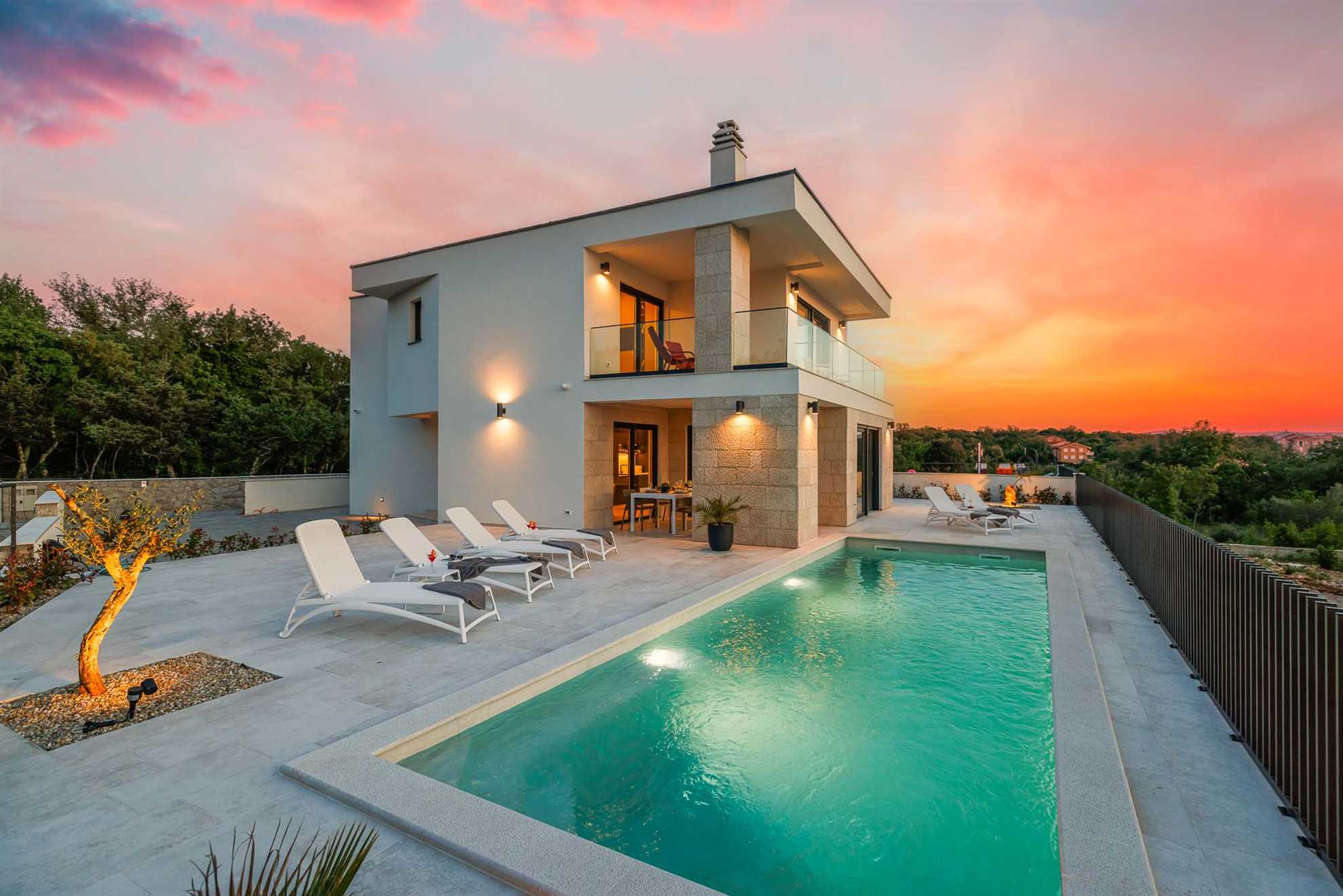 Villa AMARIS in Malinska mit Außenpool und Sonnenliegen, mit wunderschönen Farben des Sonnenuntergangs.