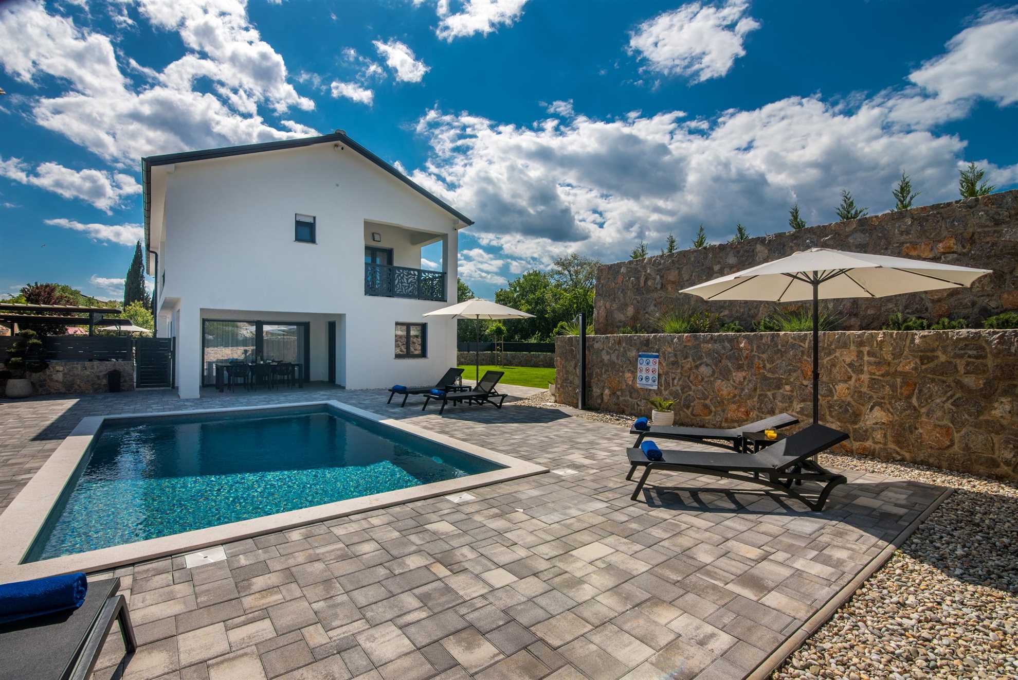 Moderne Villa Tara & Lana I mit großem Pool, Liegestühlen und gepflasterter Terrasse unter klarem Himmel