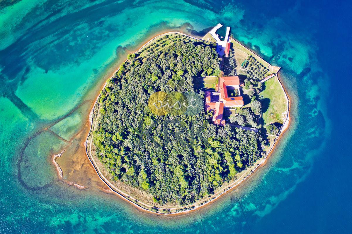 Košljun islet photographed from above, featuring a monastery surrounded by trees.