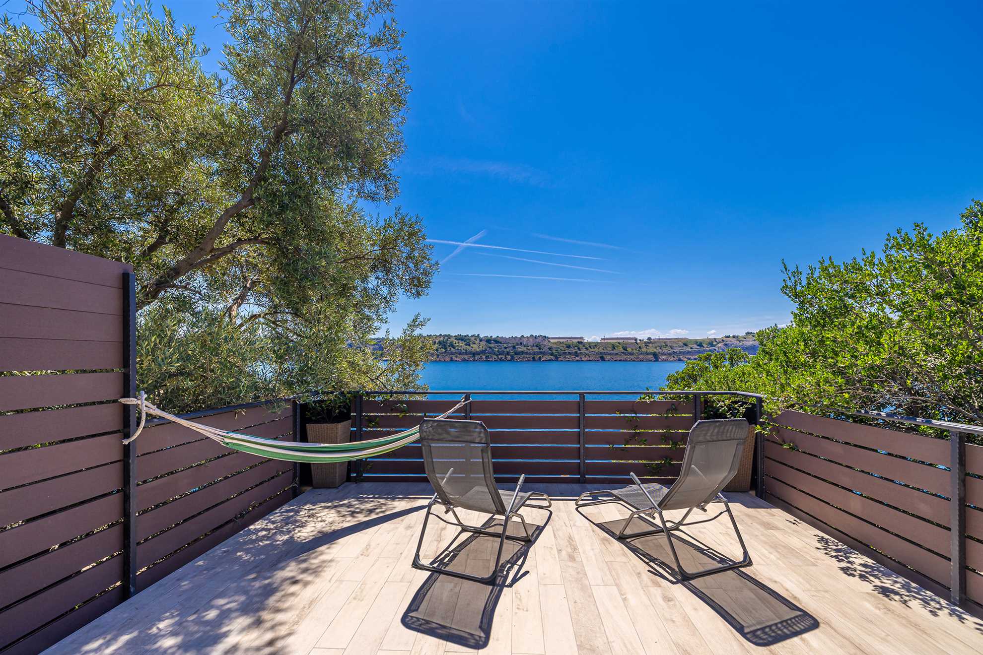 Terrasse mit Liegestühlen und Hängematte mit Meerblick