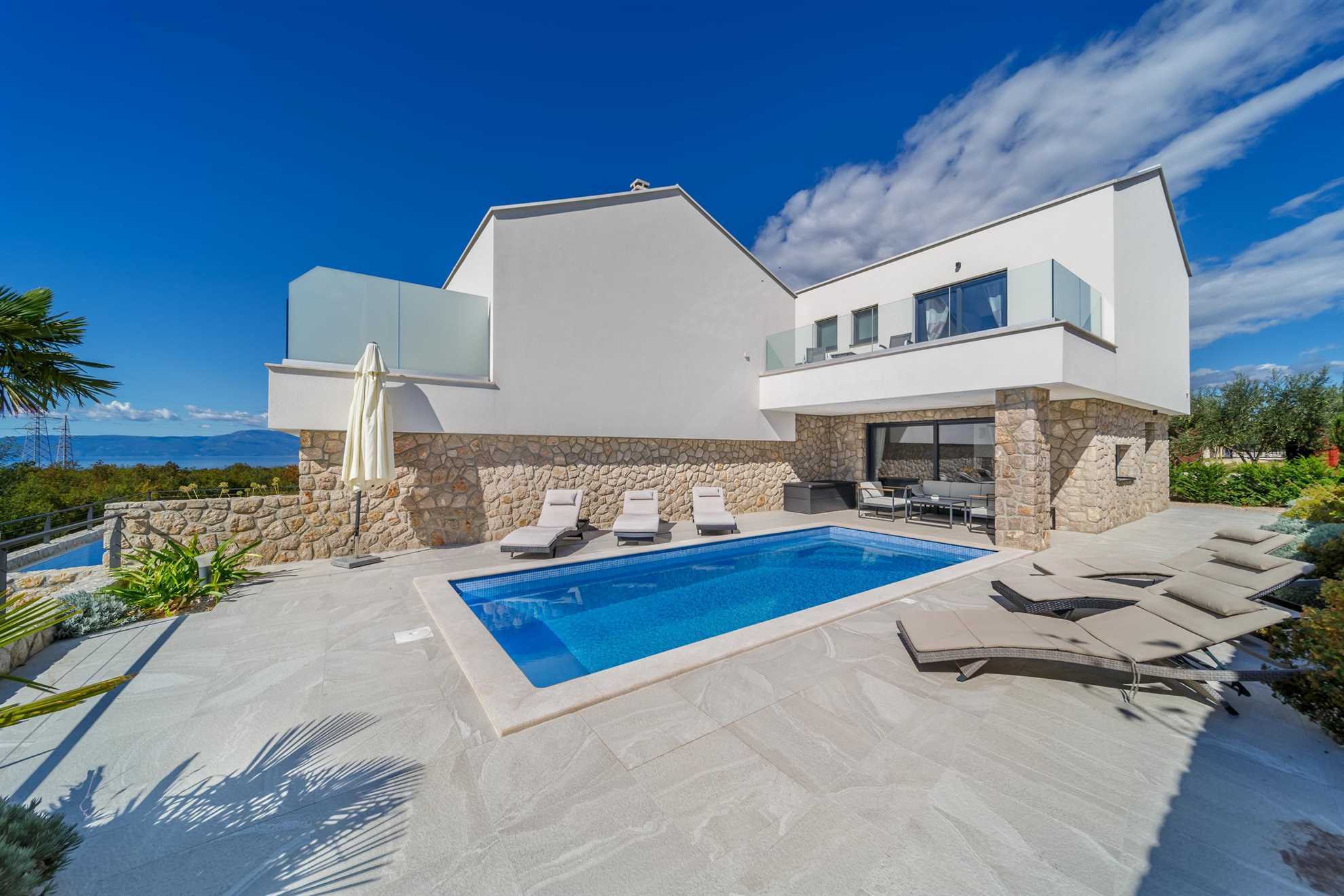 Luxury villa with a swimming pool and sun loungers.