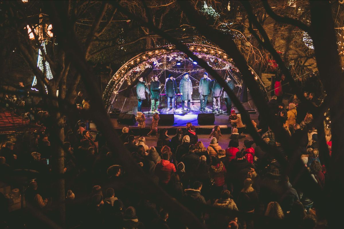 People enjoying a concert. Singers perfoming on a stage decorated with twinkling lights.