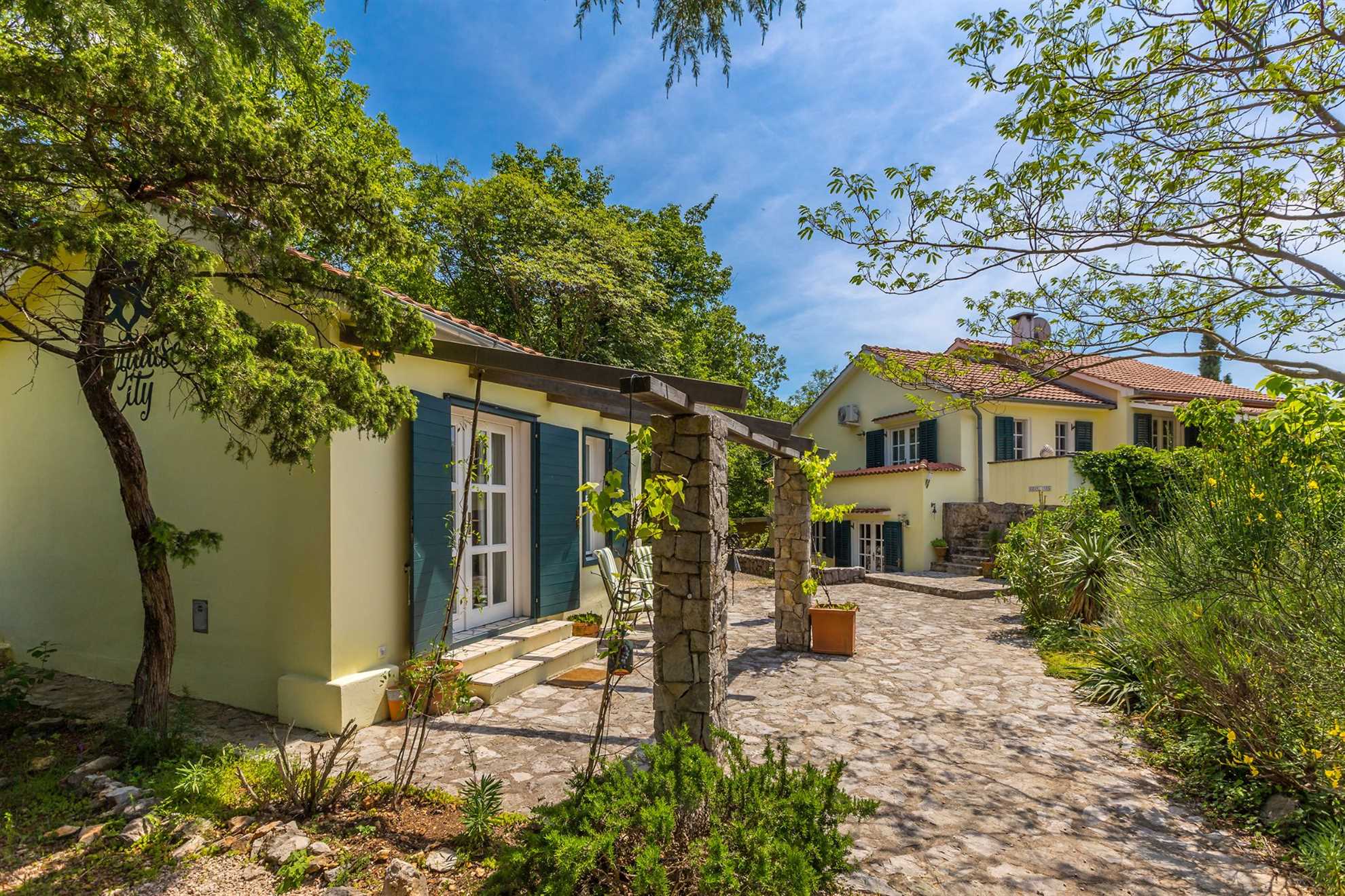 Two yellow vacation homes with a stone pathway surrounded by trees and greenery.