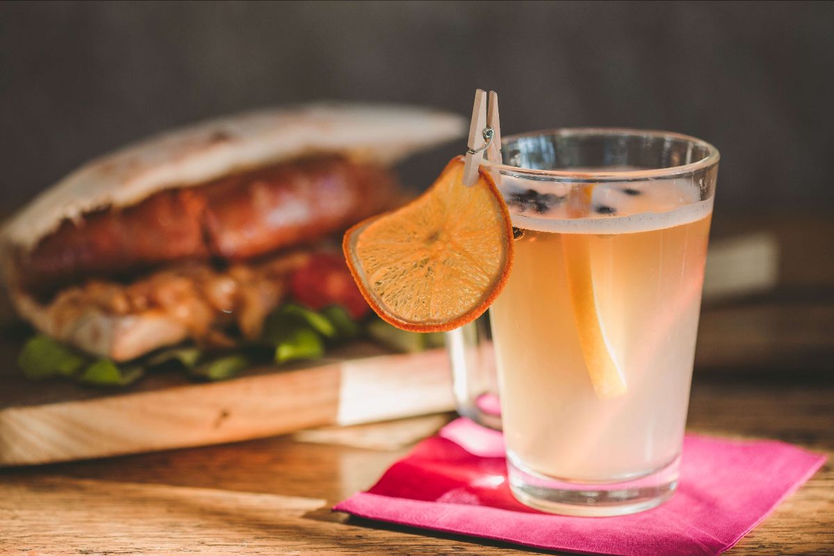 Cocktail with a slice of lemon and a delicious sausage burger