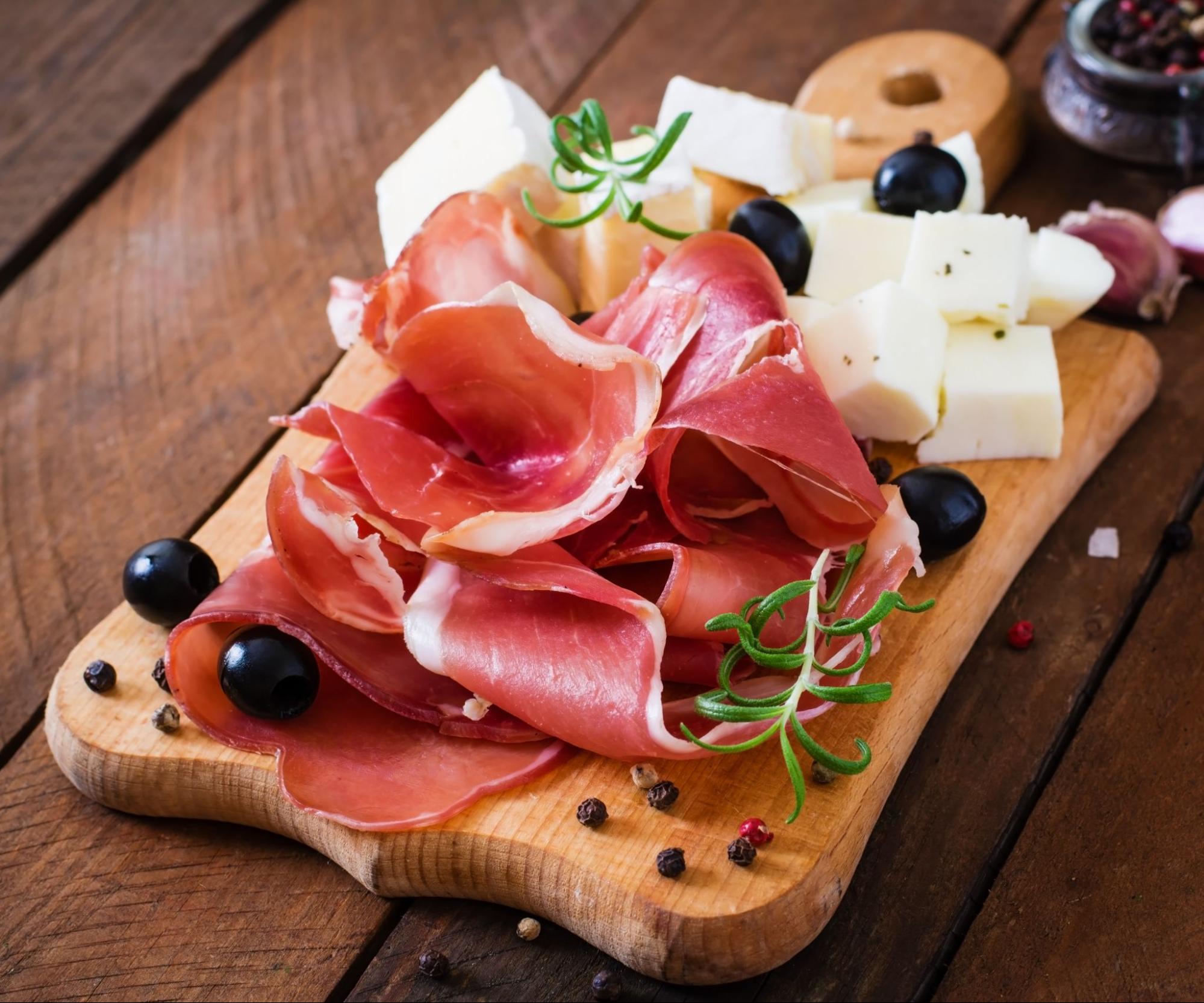 Cheese and prosciutto served on a cutting board