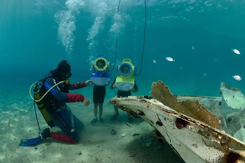 Children with diving gear and a diver exploring an underwater wreck