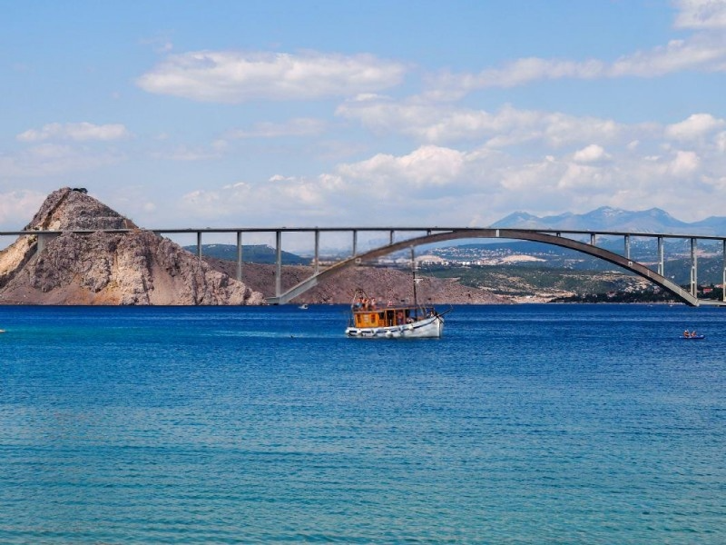 Krk-Brücke und ein Boot, das über das Meer fährt.