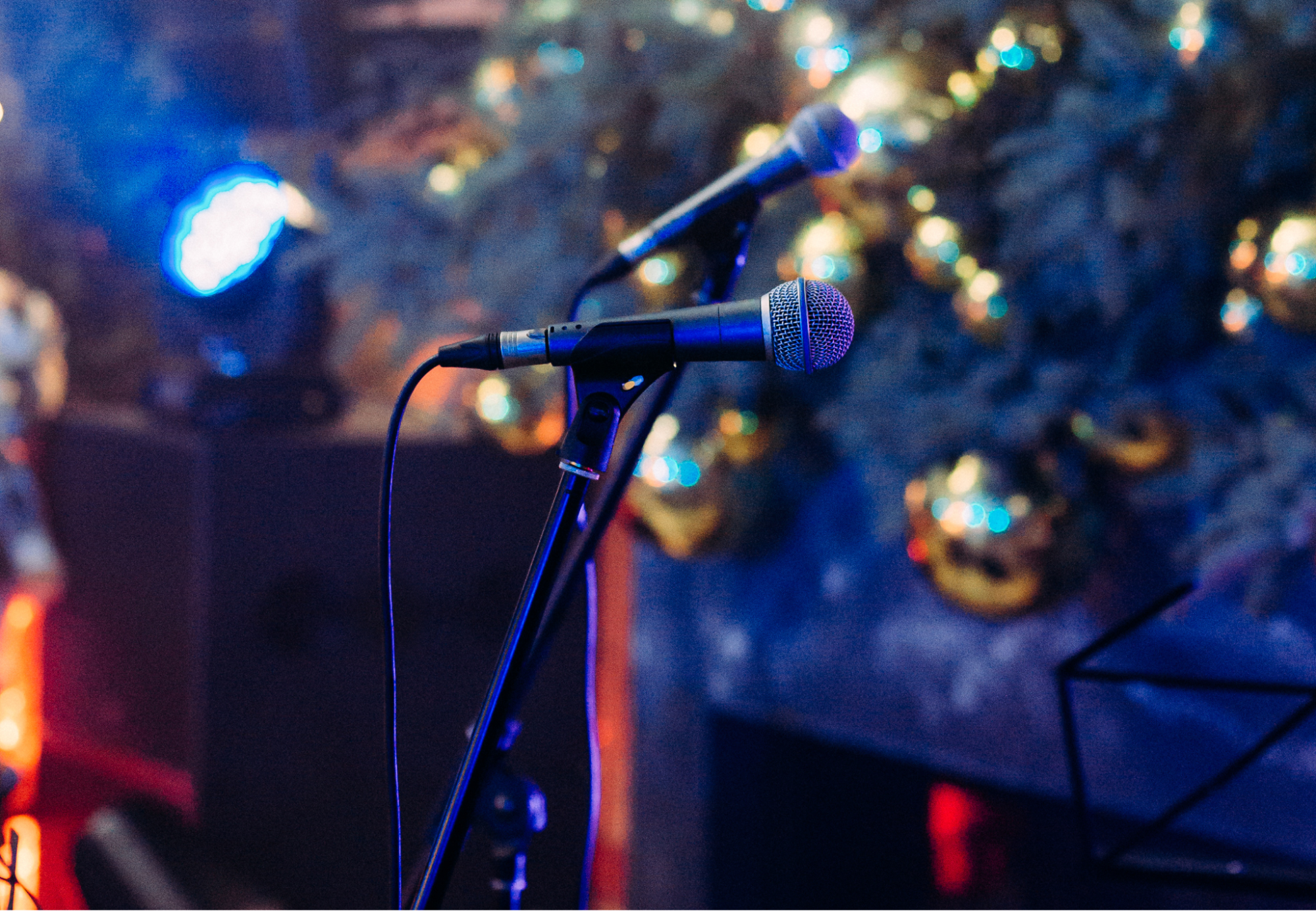 Two microphones on the stage in front of the Christmas tree.
