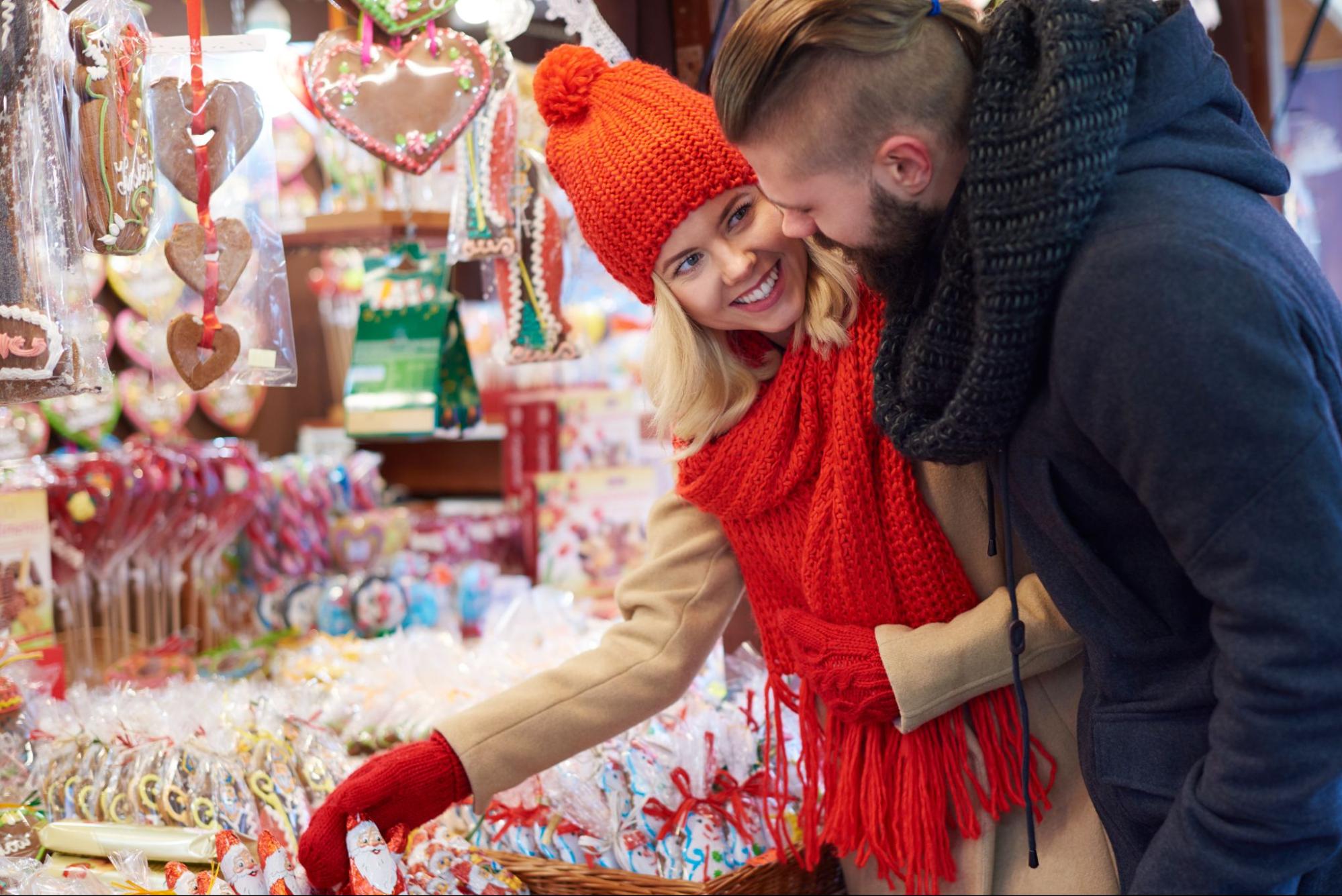 A young couple chooses sweets at an Advent stand.