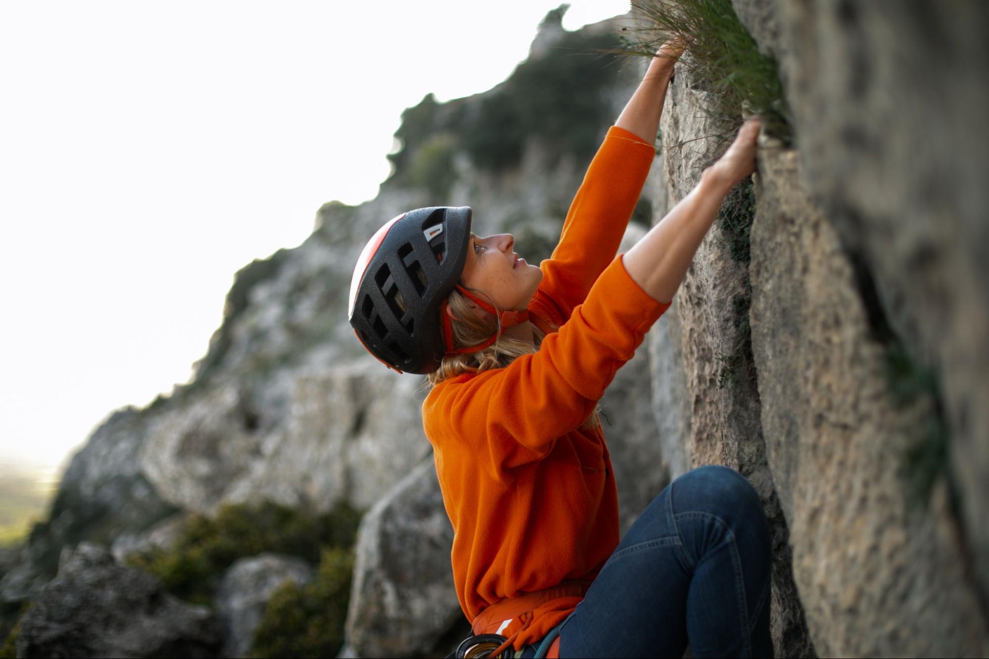 The girl is climbing on the rock. 